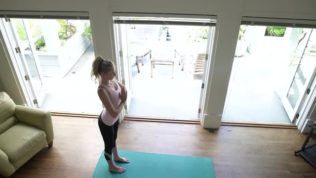 Young woman doing yoga by window