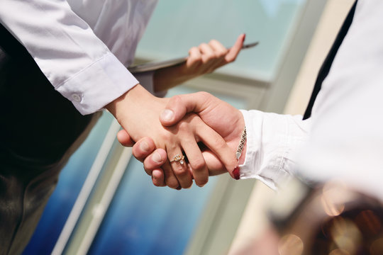 woman and man shake hands on the background of an office building.