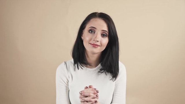  young beautiful cute brunette on a beige orange background showing gratitude, admiration, thx, thanks emotions
