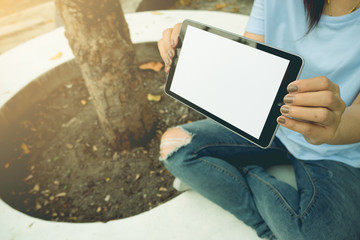 Asian women hand holding show the tablet blank screen in public park