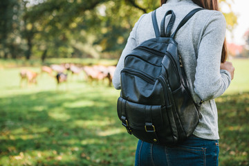 Young beautiful travel girl with backpack looking at wild reindeer grazing in the distance. The natural habitat of animals.
