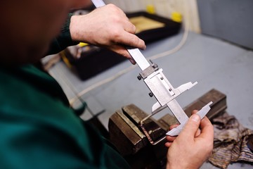close-up a worker holds a caliper in her hands and measures a detail