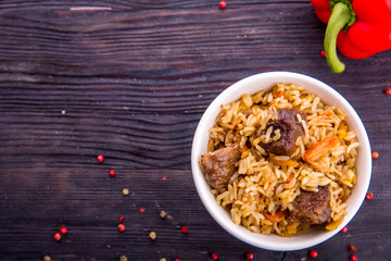 Pilaf in a flat dish with red pepper and pieces of carrots
