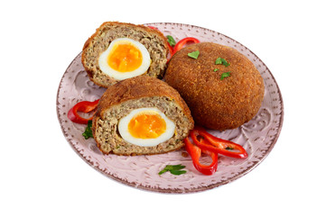 Juicy cutlet from chopped meat stuffed boiled egg on a ceramic plate isolated on a white background.