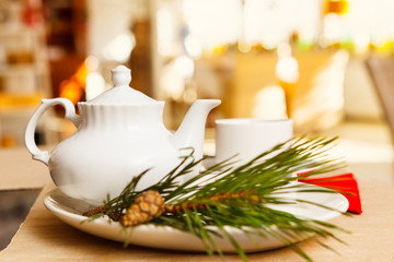 White ceramic teapot and Cup for tea, a sprig of pine in the foreground