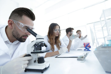 male laboratory technician looking at samples in the microscope