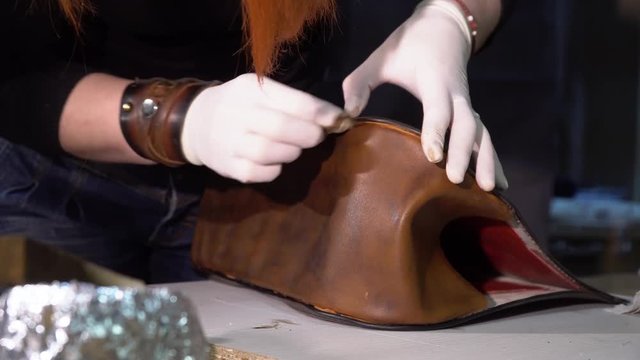 The tailor makes a handmade leather bag in the atelier