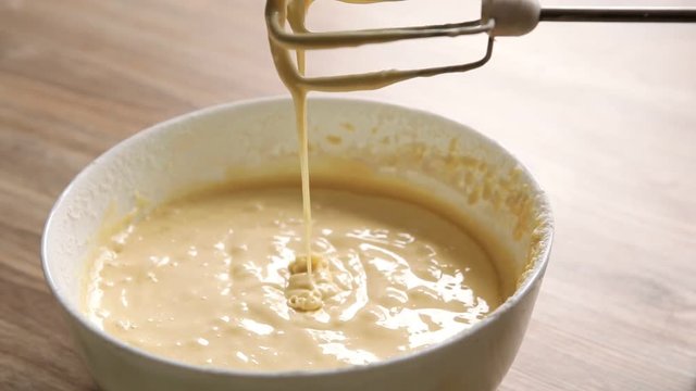 Mixing dough in bowl with motor mixer. The dough flows into the bowl.