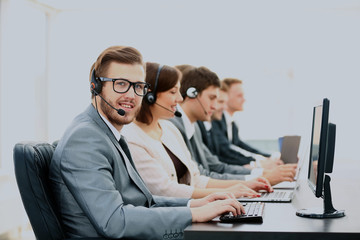Attractive young man working in a call center with his colleagues