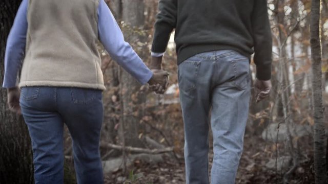 Handheld shot of senior couple walking in forest