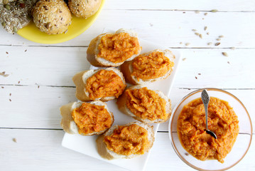Sandwiches with pumpkin dip on white wooden table. Homemade vegetable (pumpkin, paprika) sauce, top view.