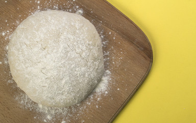 Loaf dough on wooden board on yellow background