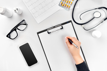 Doctor's work with stethoscope and copybook on hospital desk background. Top view