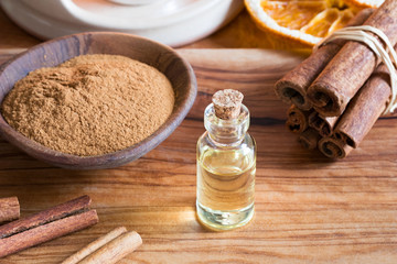 Fototapeta na wymiar A bottle of cinnamon essential oil with cinnamon sticks and powder