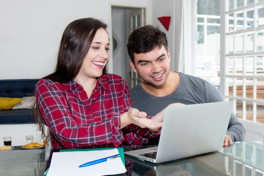 Happy young couple using computer at home