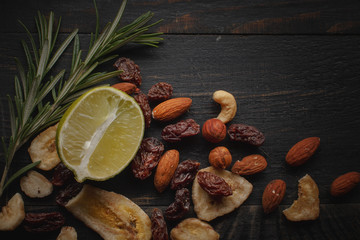 Mix of nuts, dried fruits and herbs on a black rustic background.