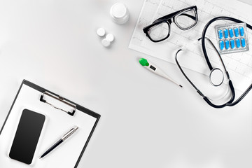 Stethoscope in the office of doctors.Top view of doctor's desk table, blank paper on clipboard with pen. Copy space. Designer's blank