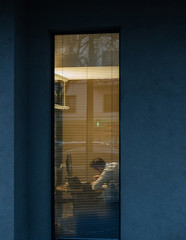 Silhouette of man seen through windows blinds working at report thesis data analysis bank report view from the street - working late concept of businessman