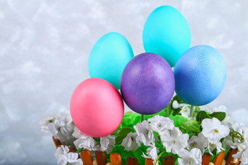 Colored Easter eggs in a basket on a gray concrete background.