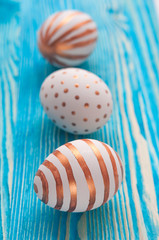 Golden Easter eggs on bright blue wooden rustic vintage background.