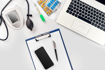 Top view of doctor's desk table, blank paper on clipboard with pen, electronic manometer to measure...