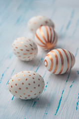 Golden Easter eggs on white wooden rustic vintage background.