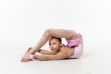 A young teenage girl in leotard shows gymnastic and ballet exercises on a white background.