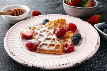 Traditional belgian waffles with fresh fruit and powder sugar on wooden board