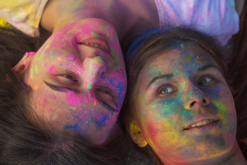 Adorable friends covered with paint Holi, lying on the asphalt