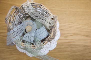 Obraz premium Cute and beautiful lace ribbons in basket on the wooden table background