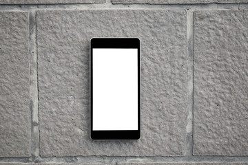 Mobile smart phone with blank screen on concrete brick plate. Technology and lifestyle concept.