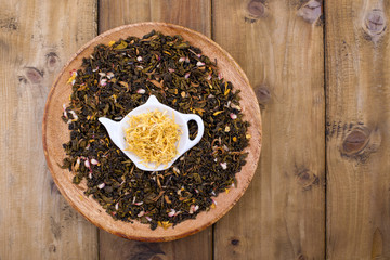 Dried herbs for tea, on a wooden round plate. Free space for text.