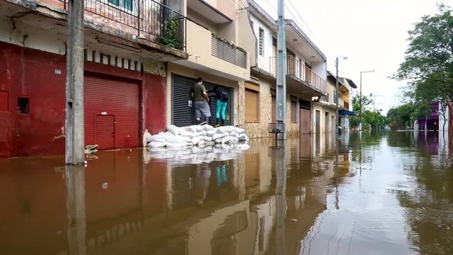 Man and woman enter a building while avoiding a flooded street