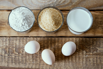 Fototapeta na wymiar fresh milk, flour, eggs and sugar on a wooden table prepared for baking a cake