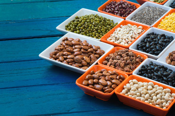 Different dry legumes in containeron blue plank, Multicolor dried beans for eating healthy