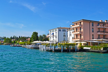 SIRMIONE, ITALY - Restaurants and Hotels sit beside the Blue Waters of Lake Garda with Blue Skies on a Summer Day