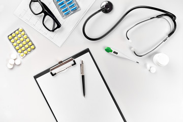 Stethoscope in the office of doctors.Top view of doctor's desk table, blank paper on clipboard with pen. Copy space. Designer's blank