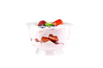 Creamy cream dessert in a plastic cup decorated with berries on a white background.