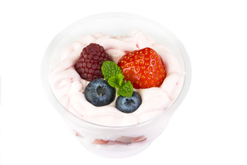 Creamy cream dessert in a plastic cup decorated with berries on a white background.