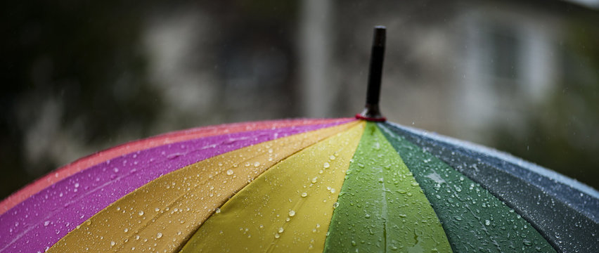 Close-up  umbrella in rainbow colors in rainy autumn day, blur focus