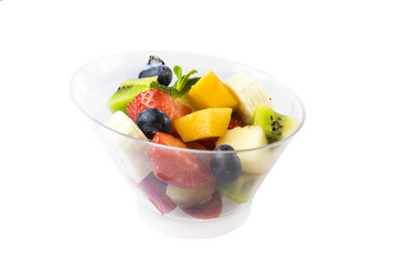 Fruit salad with bananas, strawberries, berries, in plastic utensils on a white background.
