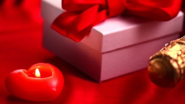 Valentine's Day romantic dinner. Date. Champagne, candles and gift box over holiday red background. 4K UHD video 3840x2160