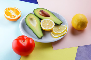 Avocado, lemon and half orange on a colorful background, tropical fruit pop art, vegetarian breakfast, Asian cuisine, avocado pop art, citrus, orange with avocado
