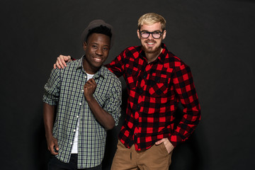 Studio lifestyle portrait of two best friends hipster boys going crazy and having great time together. On black background.