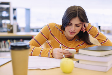 Woman using mobile phone while studying in library