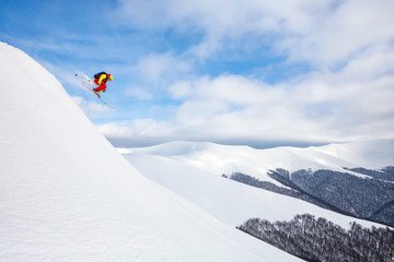 Naklejka na ściany i meble A skier is riding and jumping at mountain terrain.