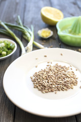 Plate of uncooked farro grains with onions, lemons, butter and rind as ingredients for a recipe