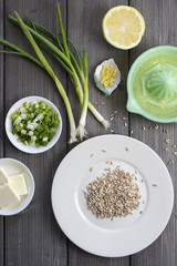 Plate of uncooked farro grains with onions, lemons, butter and rind as ingredients for a recipe