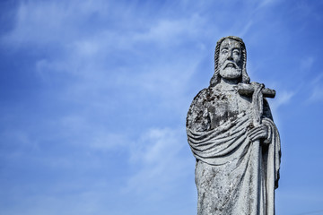 Jesus Christ ancient statue against the background of a blue sky