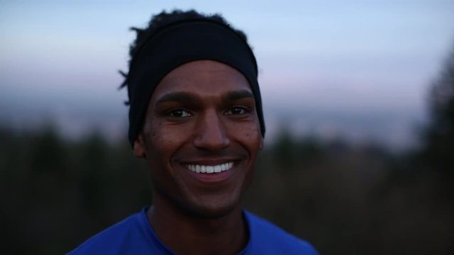 Handheld close-up portrait of happy athlete against sky at dusk